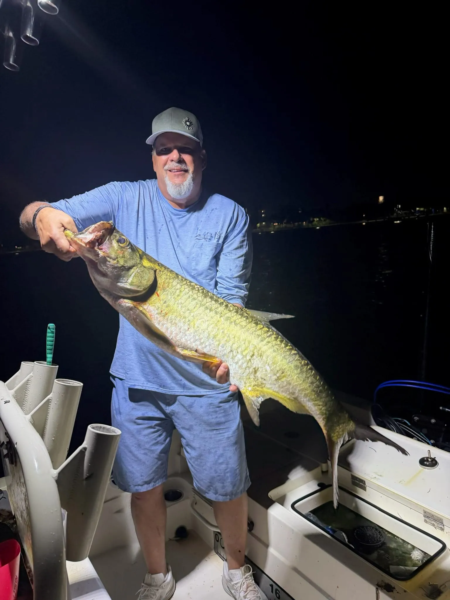 Angler holding a large tarpon caught under the dock lights on a night charter