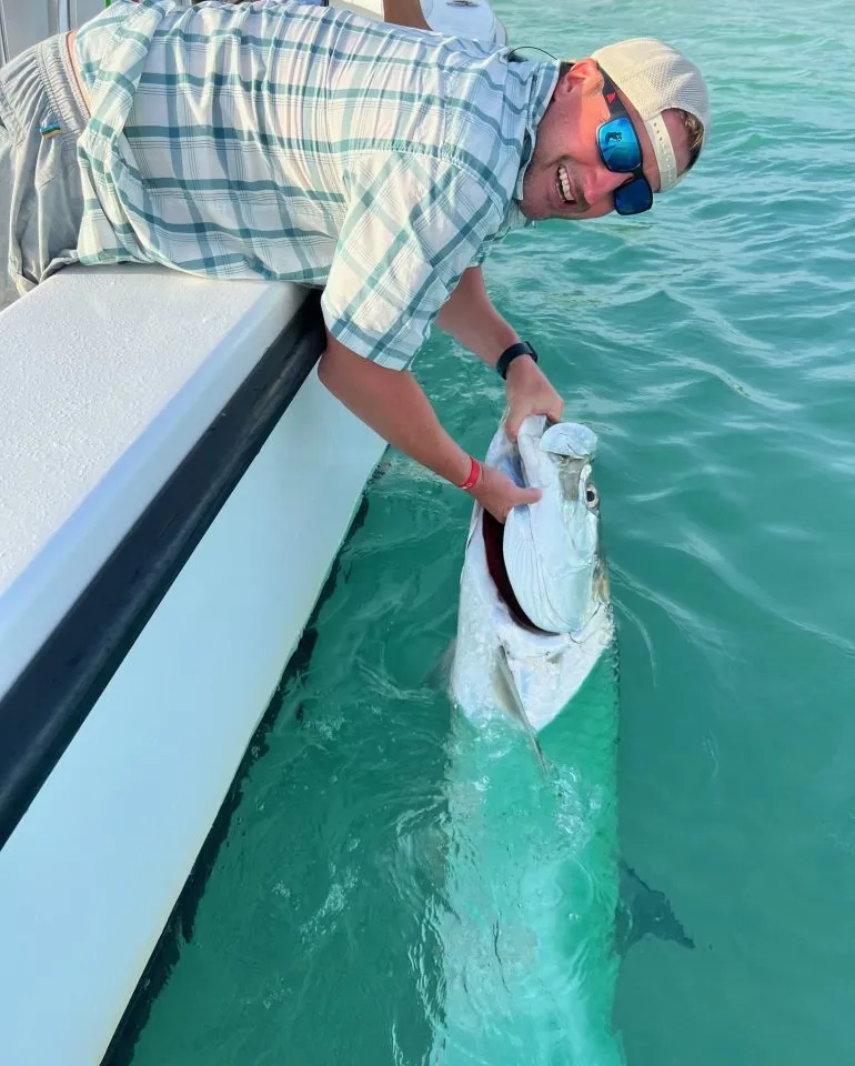 fly fishing Captain holding a tarpon on the side of the boat