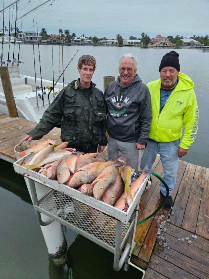 corporate fishing charters 3 men with a lot of snapper on a cutting table
