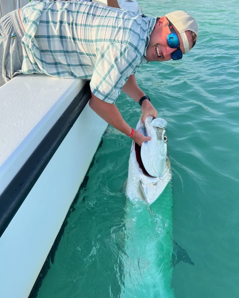 fly fishing Captain holding a tarpon on the side of the boat