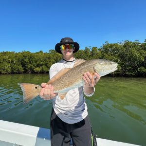 what's biting this spring Teenager holding a redfish on a boat