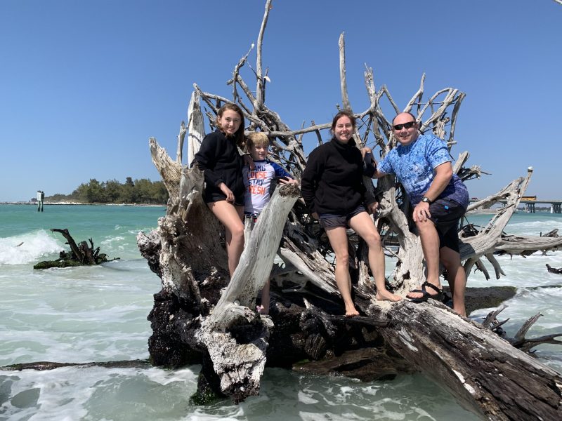 world's best beach 3 people on a driftwood treeon the beach